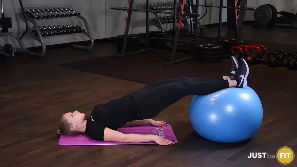 ejercicios para los glúteos, enderezando las rodillas con las piernas sobre una pelota de ejercicios