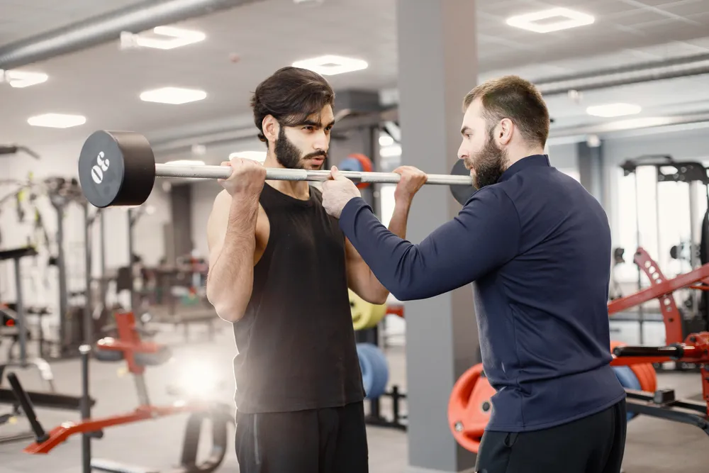 Hombre realizando entrenamiento correctivo bajo la supervisión de un especialista.