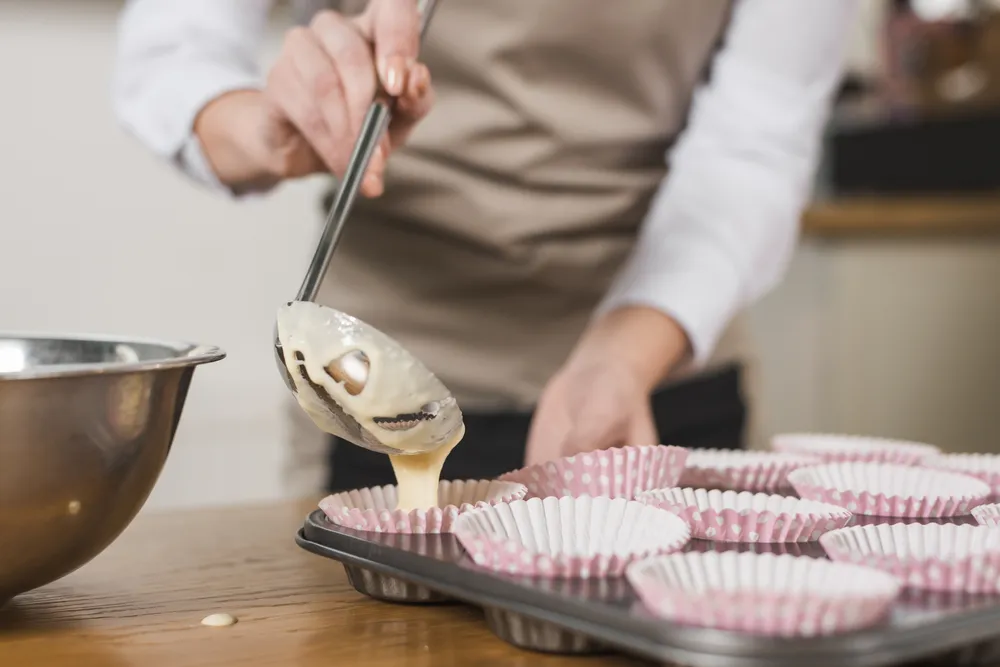 Mujer vierte masa para cupcakes en moldes