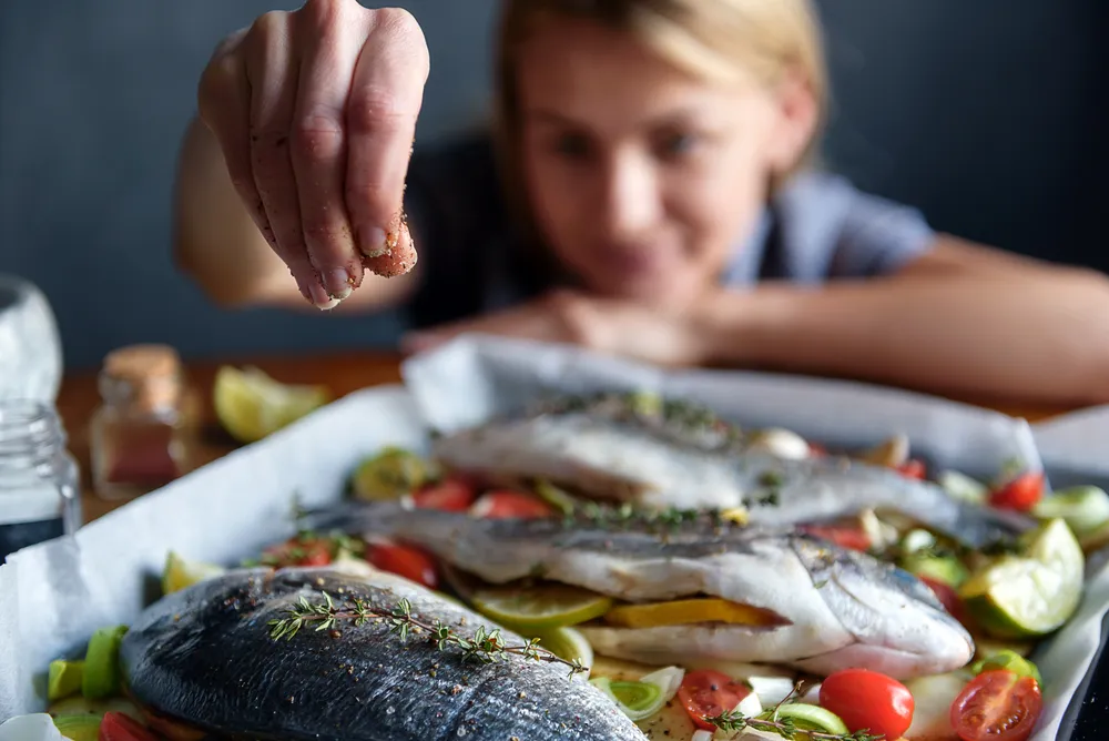 Una mujer que sigue una dieta vikinga sazona el pescado.