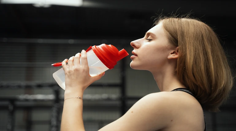 mujer consumiendo suplemento antes de entrenar