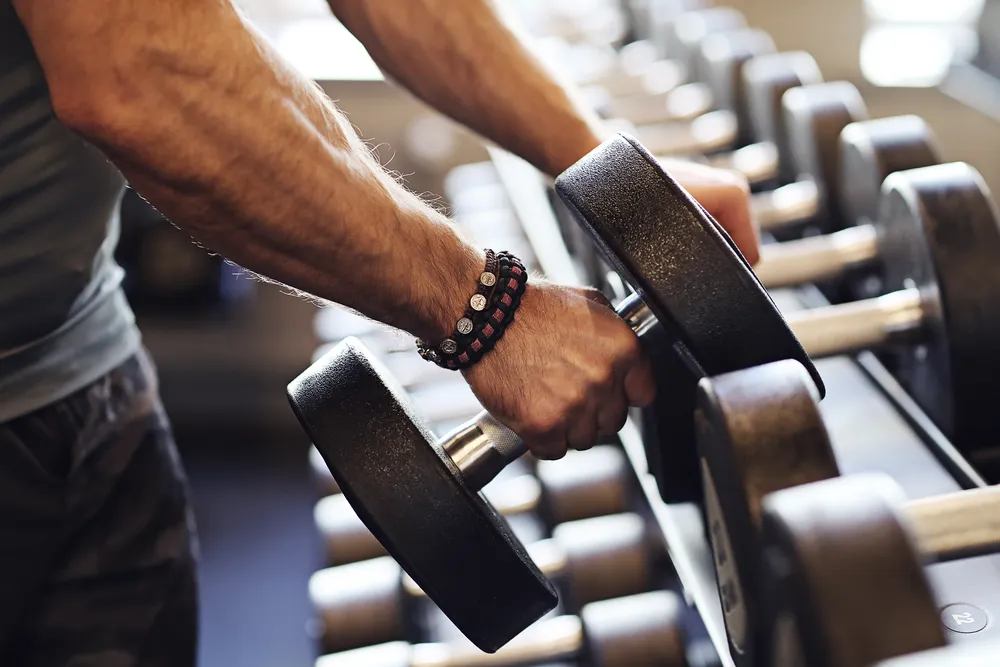 el hombre selecciona el peso para entrenar