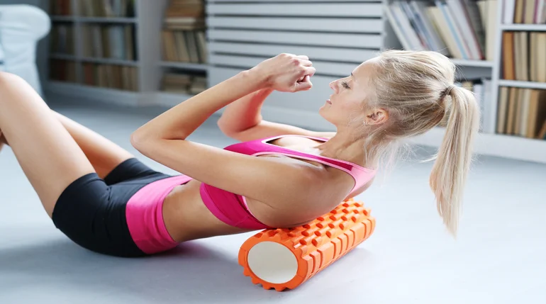 Mujer mejorando el flujo sanguíneo muscular con un rodillo.